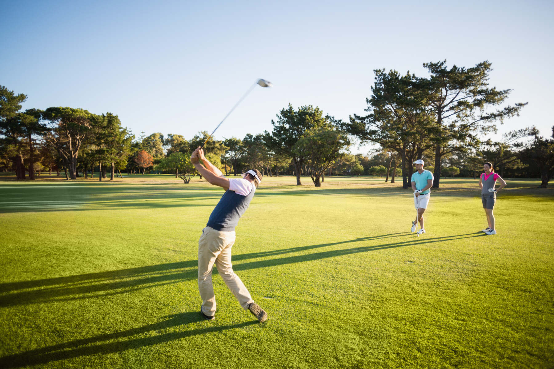 Golfer beim Abschlag auf dem Fairway, zwei Personen beobachten den Schlag bei sonnigem Wetter auf dem Golfplatz. - golf trainer karlsruhe