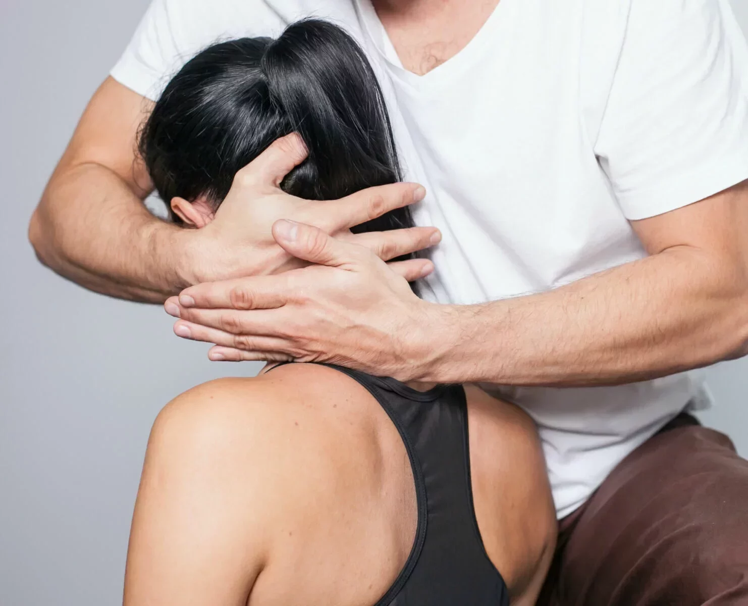 Therapeut führt manuelle Schmerztherapie am Nacken einer Patientin durch – Schmerztherapie in Karlsruhe